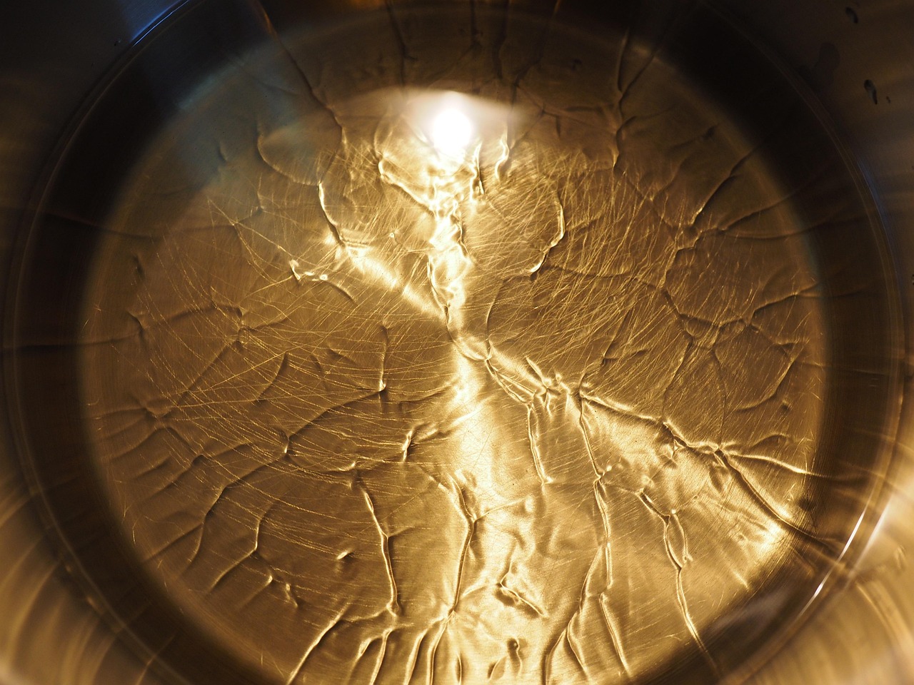 Immagine di una padella con soffritto dorato e un cucchiaio d'acqua versato nell'olio.