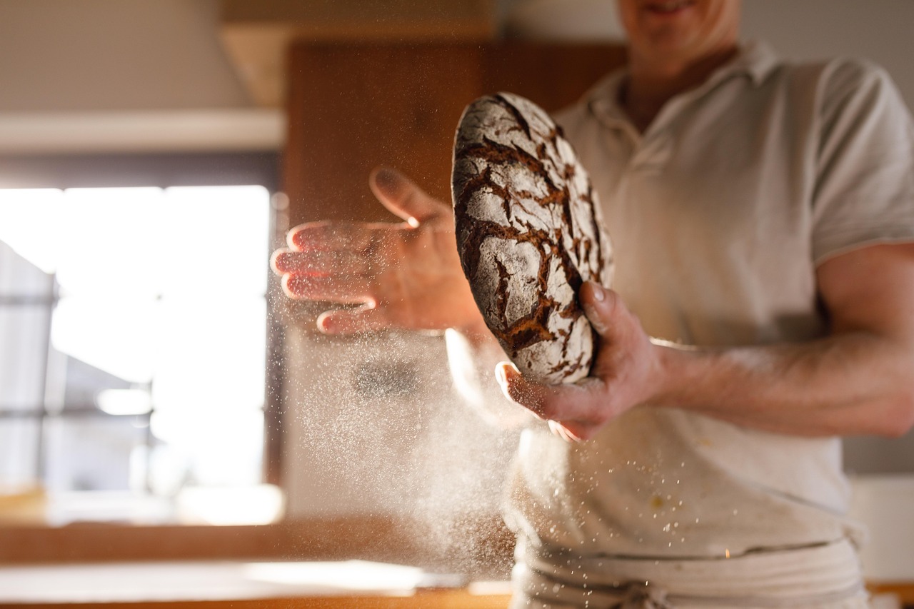 Immagine di un forno con vapore che cuoce pane fresco, evidenziando la crosta dorata e croccante.